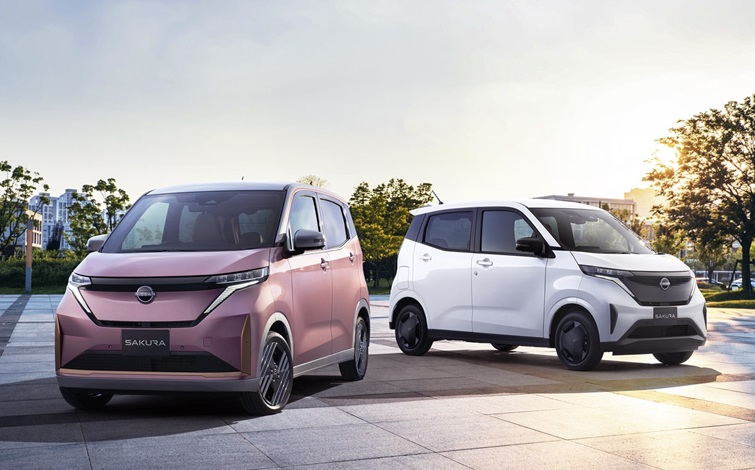 2026年4月にマイナーチェンジした日産サクラ。新色ミナモノサクラと白の2台が走行する公式画像
